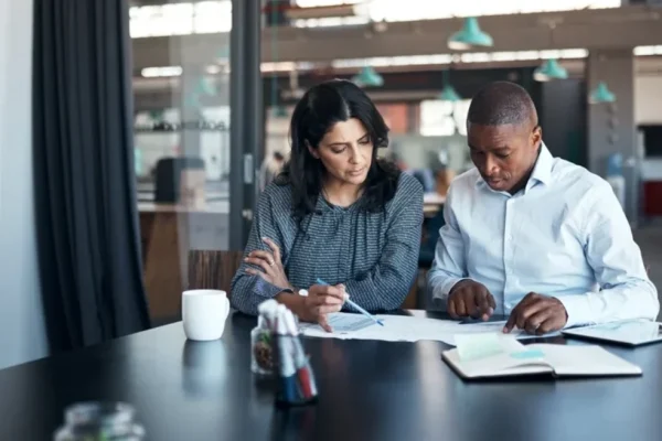 Two real estate agents sitting down at a desk, working and looking at their notes