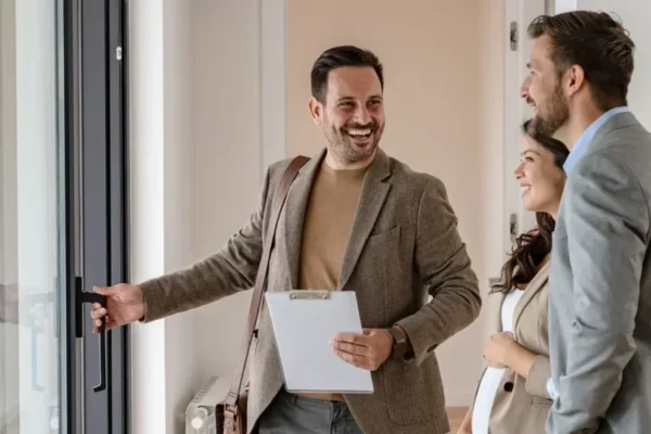 Real etstate agent eagerly giving a tour of a property to a smiling couple