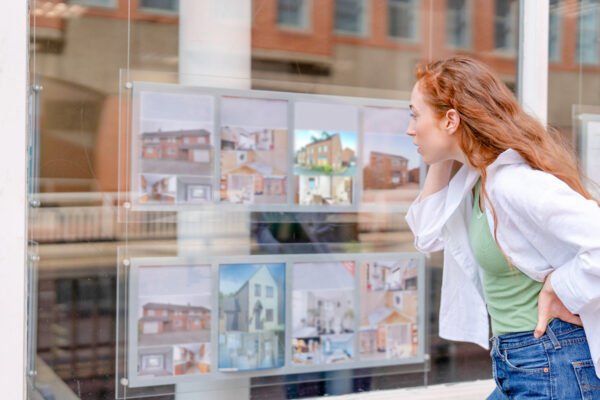 Person looking at houses for sale in an estate agent shop window